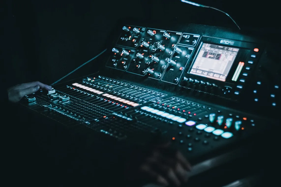 Close-up of illuminated digital mixing console in a dark venue.