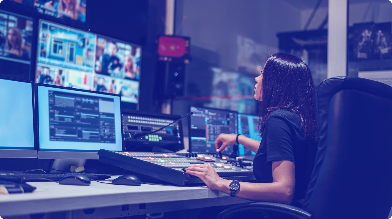 Operator switching live video feeds at a broadcast control desk.