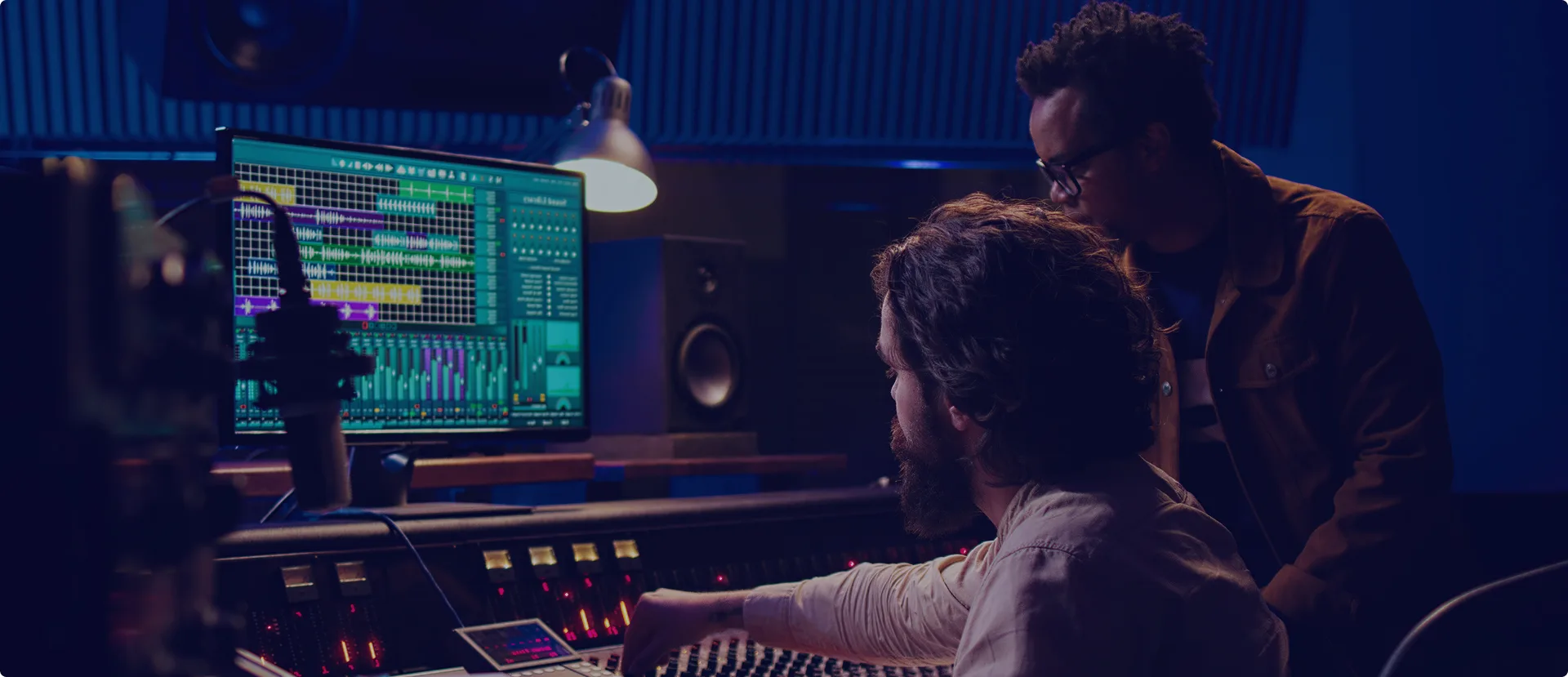 Two engineers mixing at console with DAW screen.
