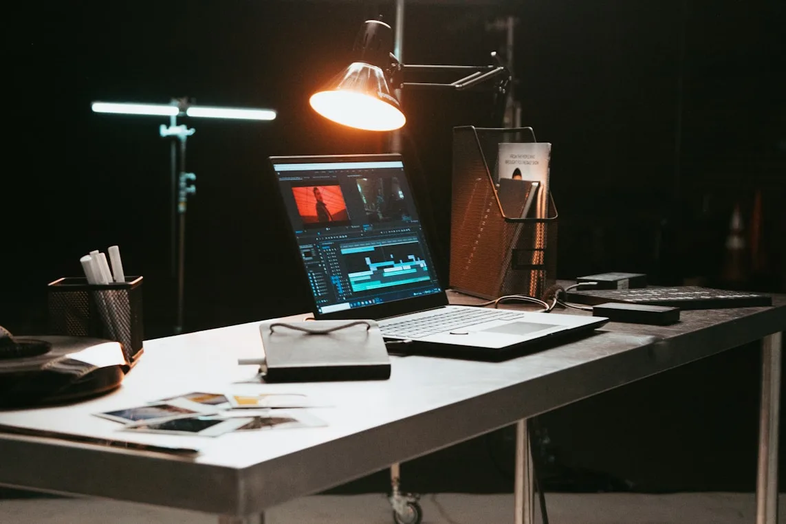 Laptop with video timeline on a lit desk in a studio.