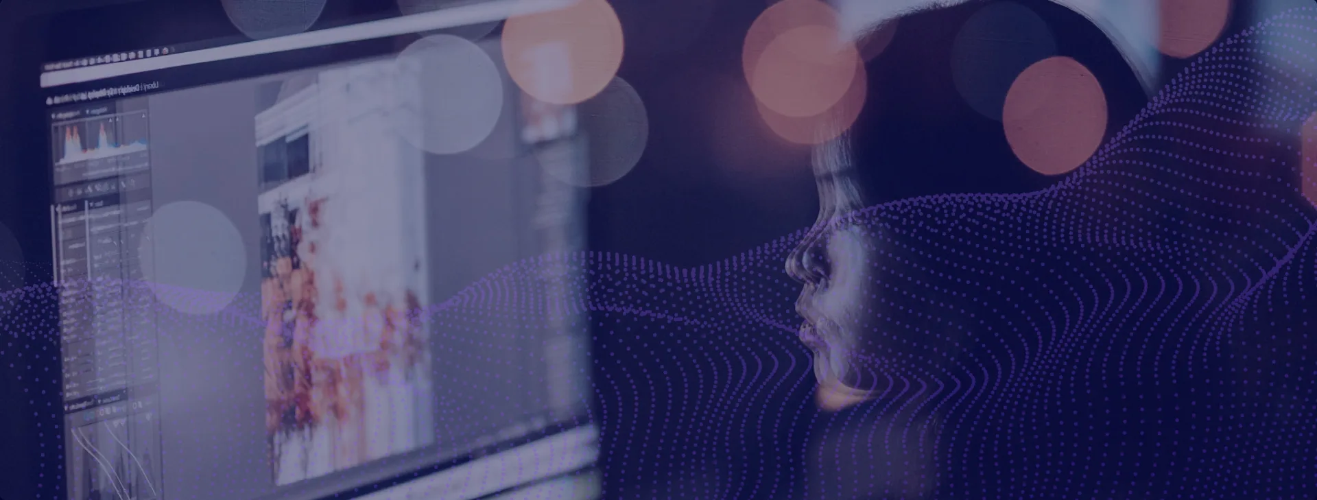 Person editing on a desktop at night with city-light bokeh reflections.