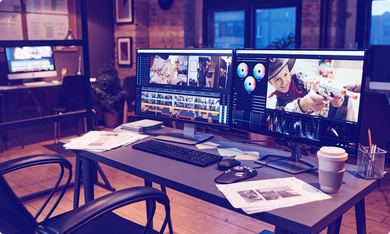 Video editing workstation with dual monitors showing timeline and color grading scopes.